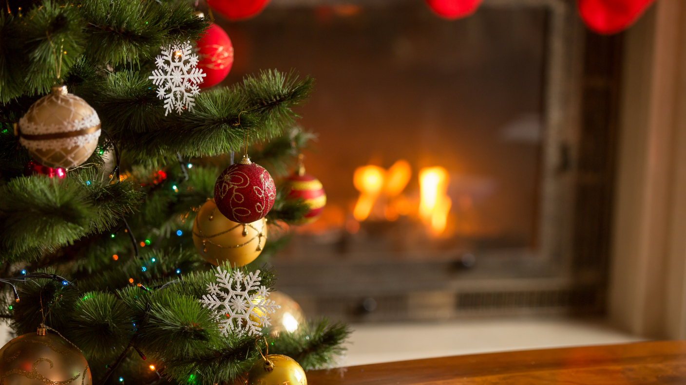 Closeup image of golden baubles on Christmas tree at fireplace