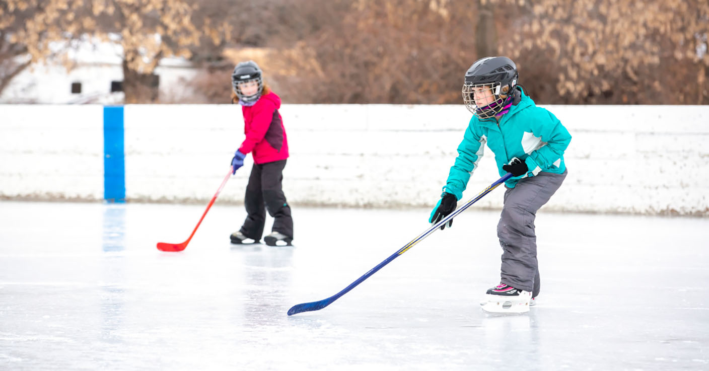 Two Girls Playing Outdoor Ice Hockey on Winter Day